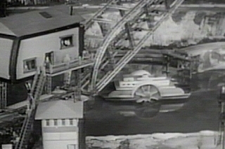 Drawbridge in Action This view of the drawbridge in action also shows reflections, this time of the ferry in the water. When the bridge is raised the ferry travels from one side of the lake to the other under the bridge. The action is captured in the Boys' Railroad Club TV program.