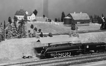 Passenger train pulled by Northern passes beneath the farm area